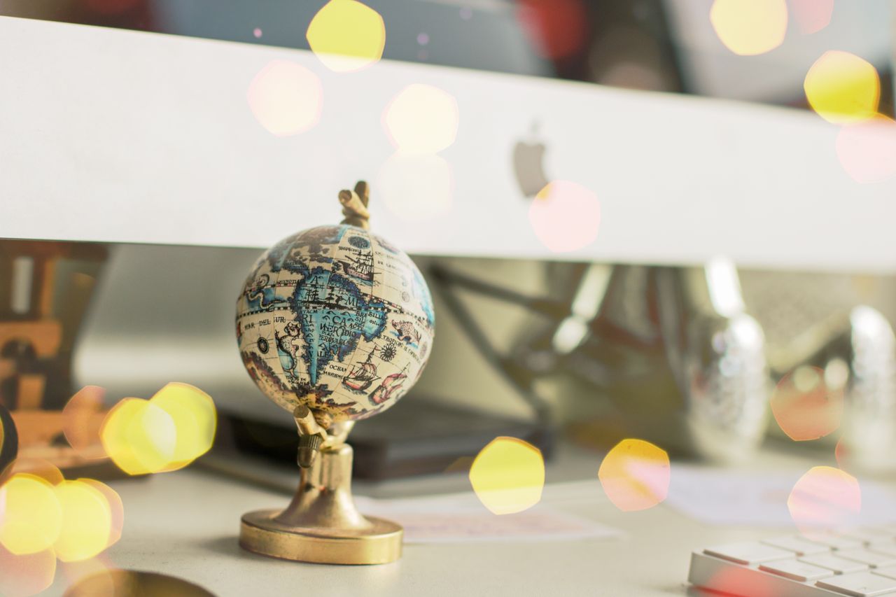 About Close-up of a miniature globe on an office desk with a bokeh light effect, creating a dreamy atmosphere.